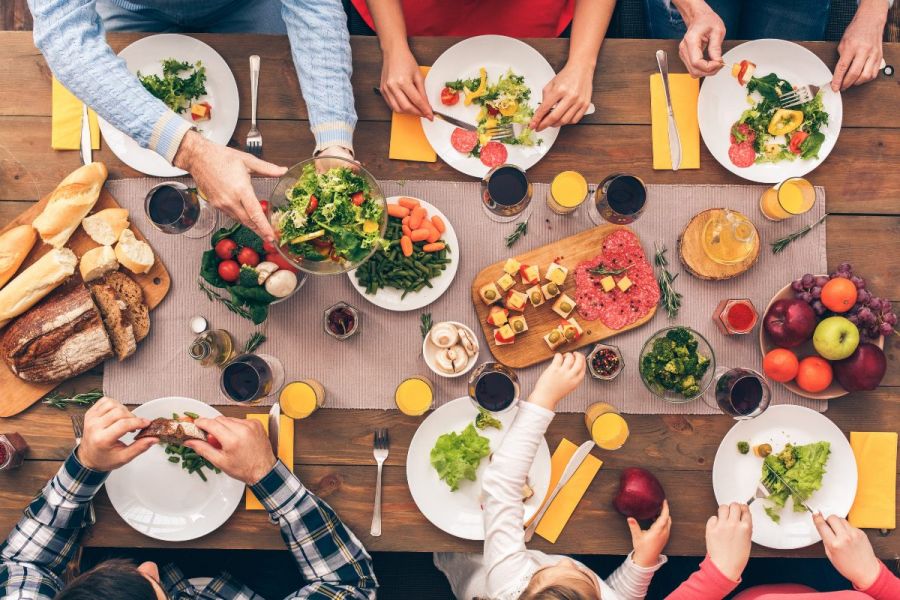 Top view of a table set for six people where a family is eating healthy food together.