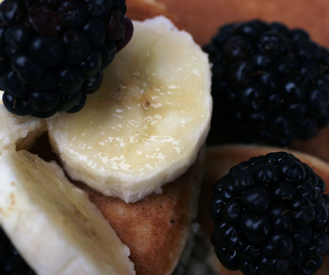 Close up of pancakes garnished with blacberries and banana.