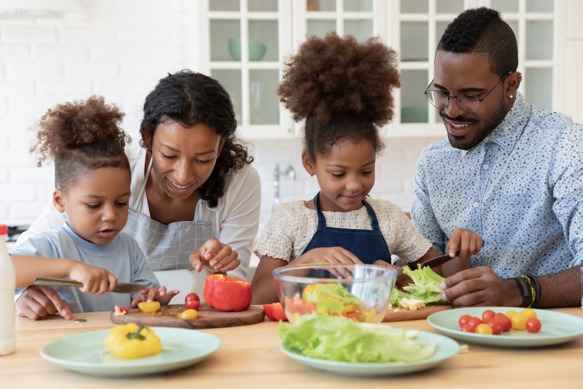 Happy couple enjoying preparing food with their daughters.