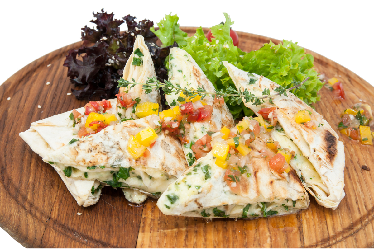 Pita bread with vegetables cut into triangles, decorated with lettuce leaves, chopped tomato and diced yellow pepper.