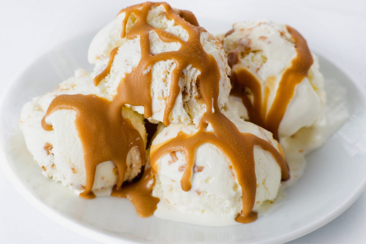 Four scoops of homecooked vanilla ice cream with caramel sauce.