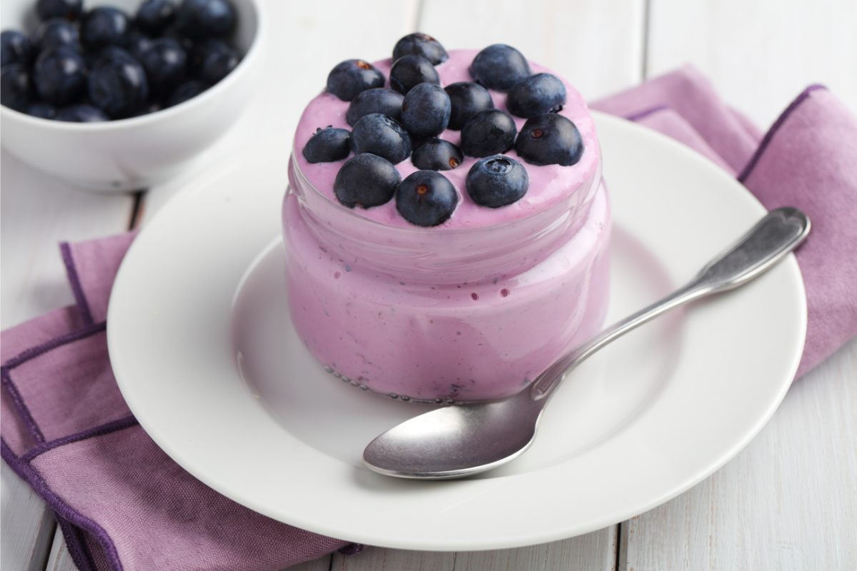 Home flavored blueberry yogurt in a pot, decorated with fresh blueberries.