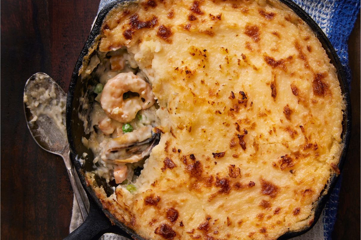 Detail of a fish pie with a crispy top of cheesy mashed potatoes.
