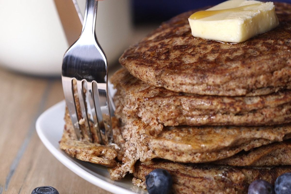 A stack of freshly cooked whole wheat pancakes with butter on top.