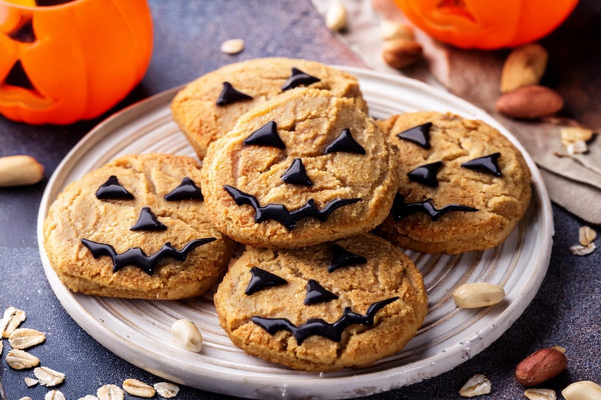 A plate with panut butter and oatmeal cookies with chocolate decorations as scary faces or pumpkin faces.