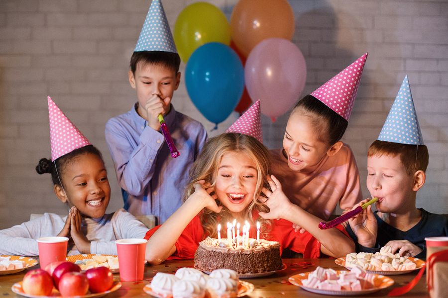Kids at a birthday party looking at the cake.