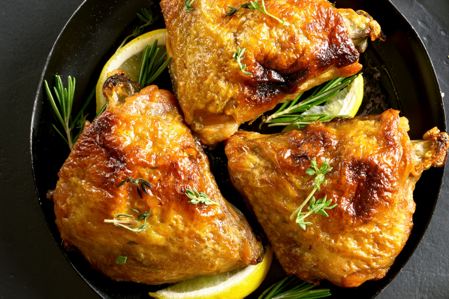 Baked chicken thighs with fresh thyme in a cast iron pan.