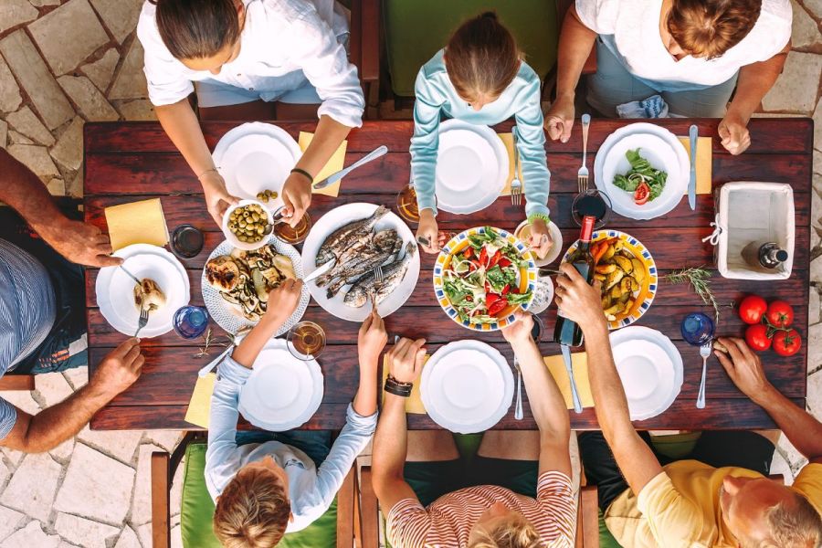 Large family sharing a healthy meal on open garden terrace.