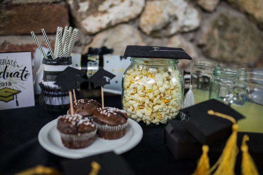A table for a graduation party with popcorn, cupcakes and decoration with a graduation motive.