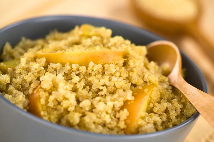 A bowl with quinoa porridge topped with apple slices.
