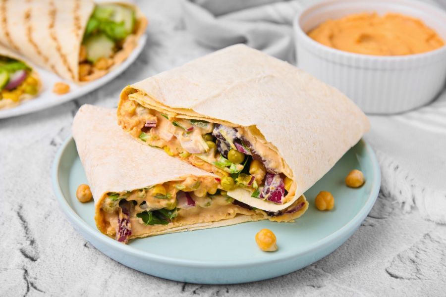 Hummus and vegetables wrap on a plate.