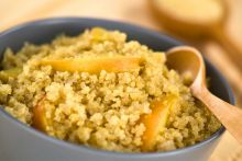 A bowl with quinoa porridge topped with apple slices.