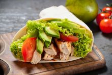 A turkey and avocado wrap on a chopping board.